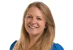 Lucy Collins, smiling at the camera, wearing a blue top against a plain white background.