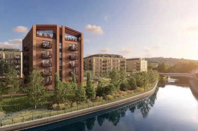 A CGI of Bath Regeneration: A riverside residential development featuring modern multi‑storey apartment buildings, landscaped green spaces, and a calm stretch of water running alongside the site under a bright sky.