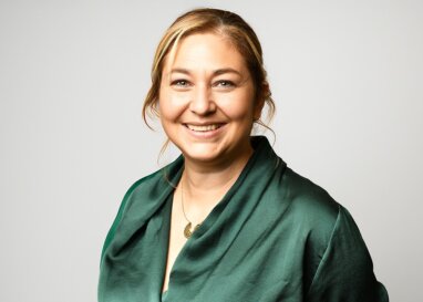 Gemma Millard wearing a dark green blouse against a light background.