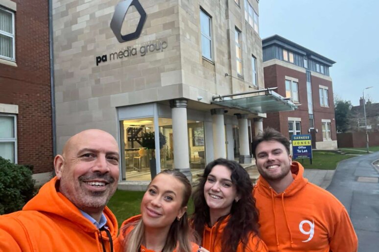 a group photo of the Nine Feet Tall team wearing orange hoodies