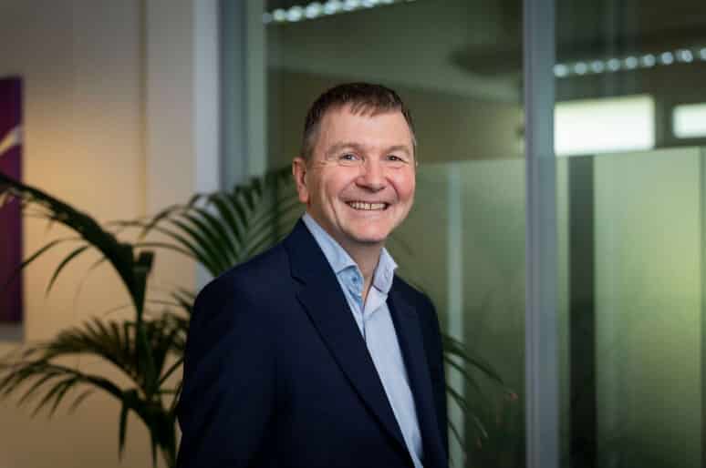 Simon Holdsworth of Thrings smiling and wearing an open-necked blue shirt and smart jacket